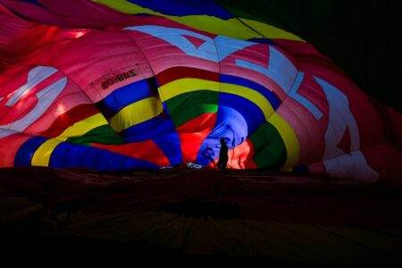 Inflation : pourquoi le moral économique des Français décroche malgré le reflux des prix Silhouette of person inside a brilliantly lit colorful hot air balloon during dusk.