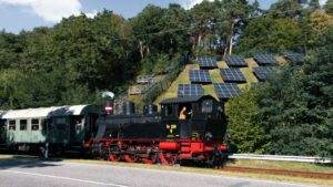 Historical steam locomotive beside modern solar panels, blending nostalgia with technology.
