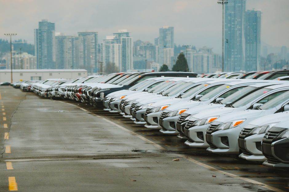 White cars lined up in a parking lot with a city skyline backdrop.