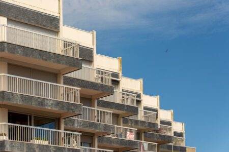 Taux d’usure immobilier 2026: pourquoi sa remontée ne règle rien pour les acheteurs A modern apartment building with distinct balconies against a clear blue sky.