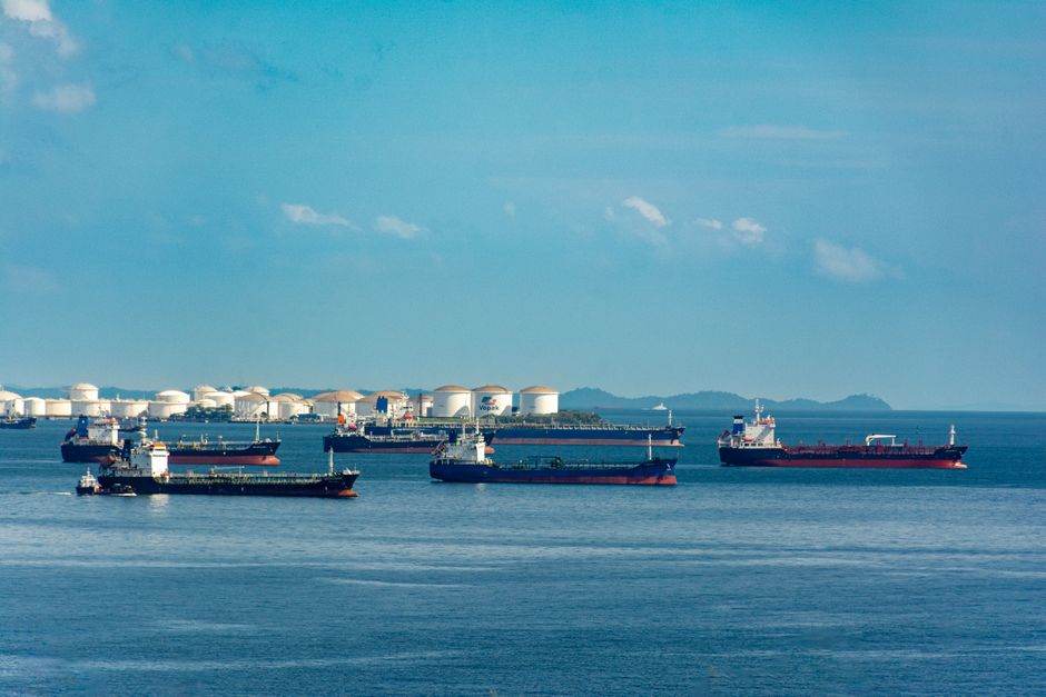 Oil tanker navigating a narrow strait at sunset