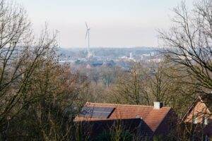 Facture d’électricité démentielle : quand un fournisseur vous facture la consommation d’un village View of Coesfeld with solar panels on rooftops and wind turbines in the distance.