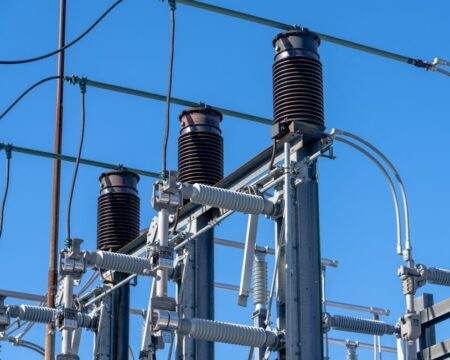 Réforme des taxes 2026 sur l’électricité et le gaz : qui paie plus, qui paie moins ? Detailed view of electrical components in a power substation under a clear blue sky.