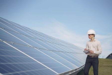 Chèque énergie 2026 : calendrier d’envoi par département, montants, pièges à éviter Young serious male engineer in formal outfit and helmet reporting while inspecting solar panel field