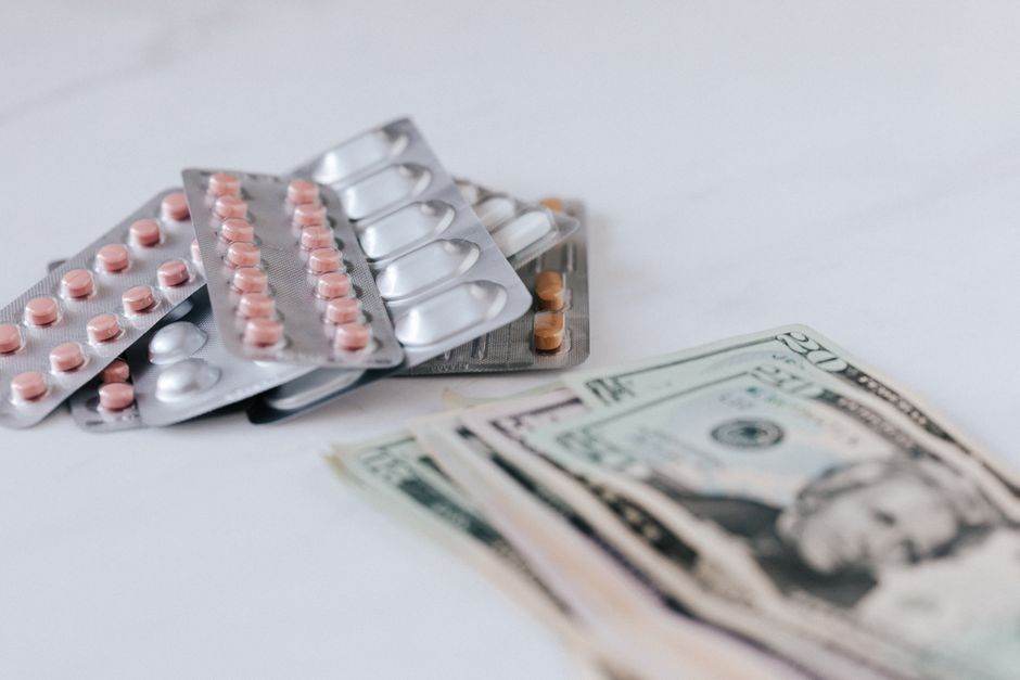 Prix de l’électricité mars 2026 : ce que les fournisseurs préparent vraiment pour votre facture Multicolored pills in silver blisters on white surface near heap of paper money representing expensive pharmacy
