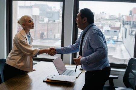 Changement d’adresse Pôle emploi, ce qu’il faut faire pour éviter un dossier bloqué Young female candidate shaking hands with employer before job interview in light office with urban landscape through windows