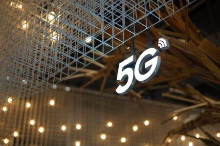 5G dans l’espace, la bascule vers les satellites en orbite basse Illuminated 5G sign with modern geometric ceiling and warm lighting.