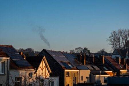 Chèque énergie 2025 : que change la crise politique pour le versement et les dates ? A row of houses displaying solar panels on their rooftops, reflecting sustainable energy practices.