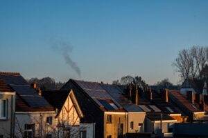 A row of houses displaying solar panels on their rooftops, reflecting sustainable energy practices.