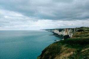 Picturesque scenery of endless stony coast covered with green grass and moss near calm rippling water of ocean