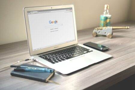 Starlink : ce que change la nouvelle autorisation de l’Arcep en France A neat workspace featuring a laptop displaying Google search, a smartphone, and a notebook on a wooden desk.