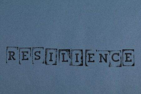RESILIENCE printed in vintage style on a textured blue background paper.