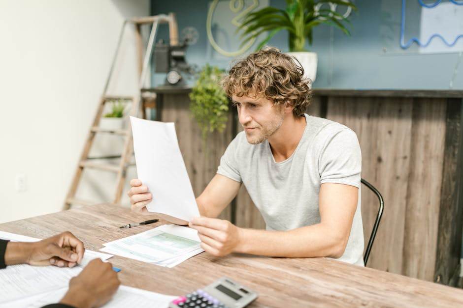 Offre Happy Heures Vertes d’Engie : vraie économie ou mirage marketing ? A man with curly hair evaluates documents at a desk, highlighting focused work in a professional setting.