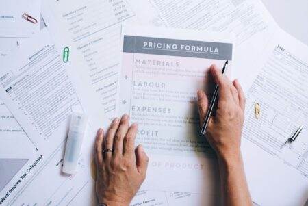 Gaz : pourquoi les prix ne reviendront jamais à ceux d’avant-guerre en Ukraine Hands organizing business documents and pricing formula papers on an office desk.