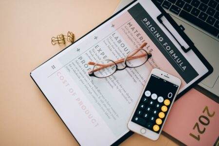 Engie casse les prix du gaz en mars 2026 avec un kWh bloqué à 0,0984 euro sur trois ans Overhead view of business tools including a phone calculator, pricing formula document, and eyeglasses on a desk.
