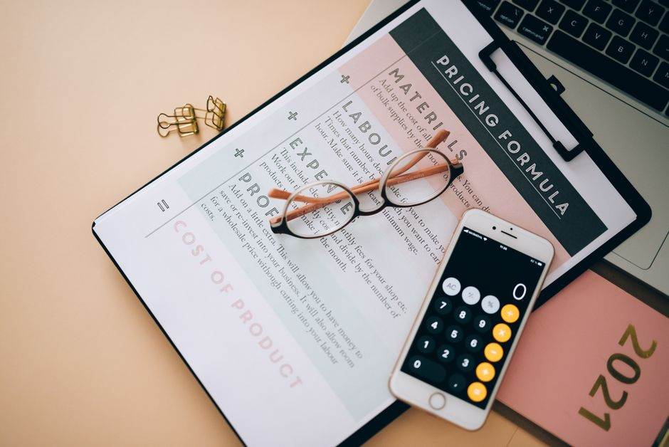 Engie casse les prix du gaz en mars 2026 avec un kWh bloqué à 0,0984 euro sur trois ans Overhead view of business tools including a phone calculator, pricing formula document, and eyeglasses on a desk.