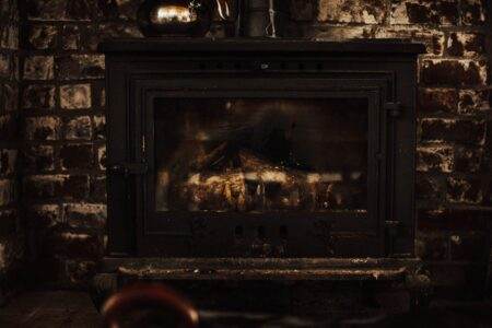 A warm and inviting vintage fireplace against a rustic brick wall, perfect for cozy winter settings.