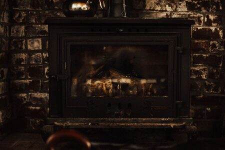 A warm and inviting vintage fireplace against a rustic brick wall, perfect for cozy winter settings.