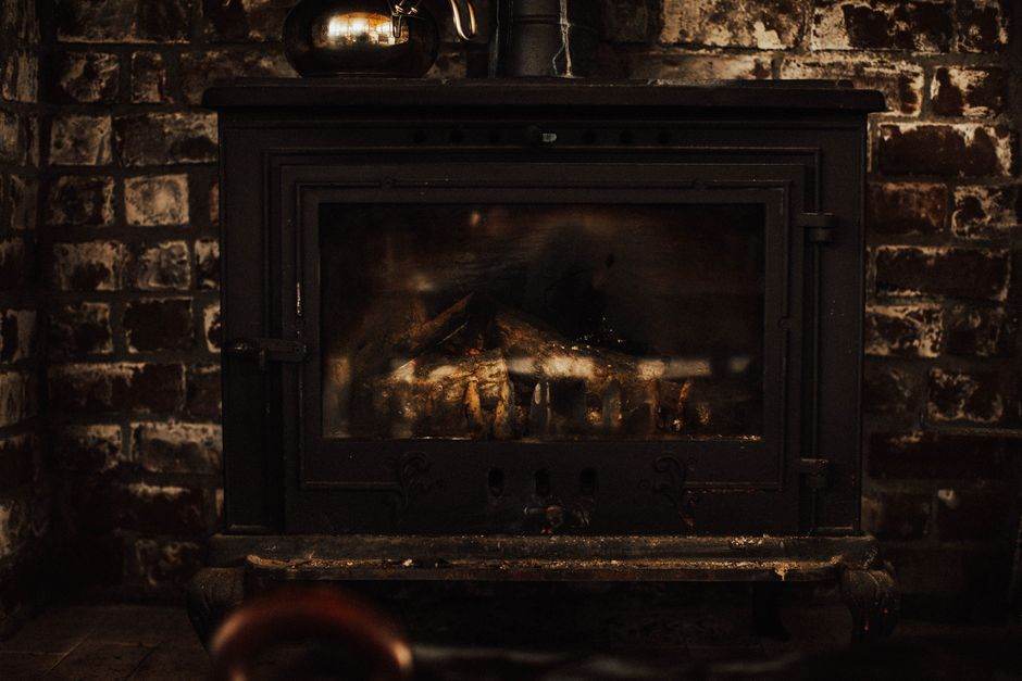 Neige en plaine, gel et tension sur le chauffage : comment protéger votre logement sans exploser la facture A warm and inviting vintage fireplace against a rustic brick wall, perfect for cozy winter settings.