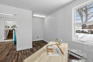 a white room with wood flooring and a large window