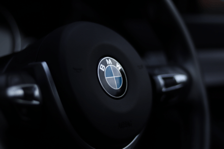 Bons plans et offres moto BMW : quand une promotion peut vraiment changer votre projet Detailed view of a BMW steering wheel emblem with a stylish depth of field effect.