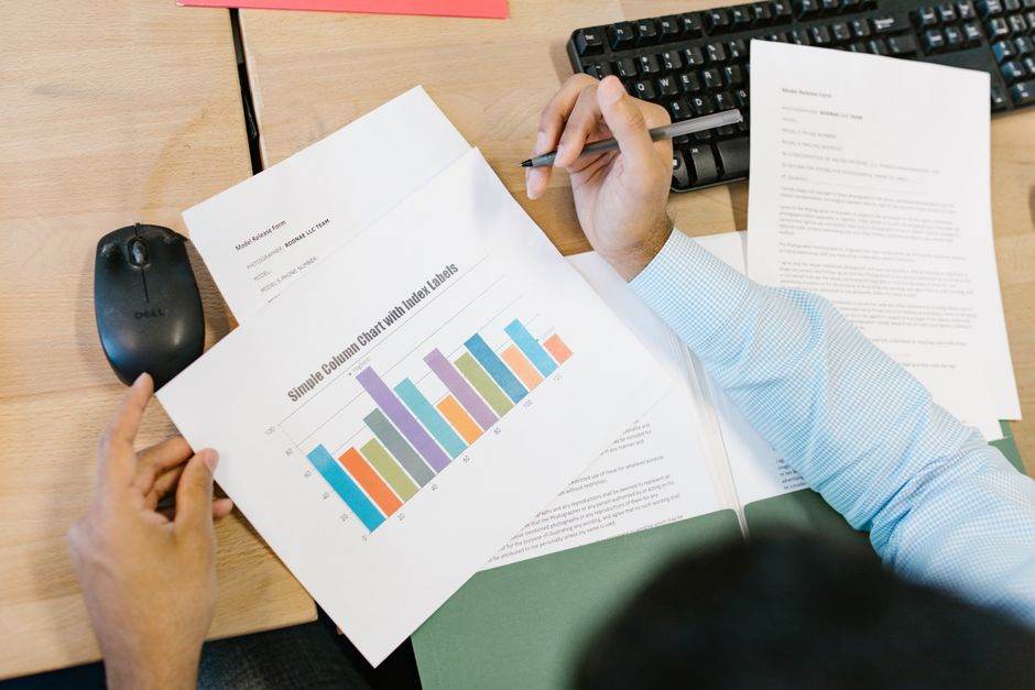 Pembrolizumab : trois cancers, trois résultats à nuancer A business analyst reviews a colorful bar chart and documents at a desk, indicating data analysis.