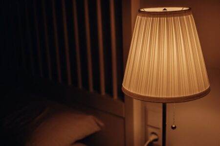 Sleepal AI Lamp : le suivi du sommeil sans montre, avec abonnement A dimly lit bedside lamp creating a warm and cozy atmosphere in a bedroom setting.
