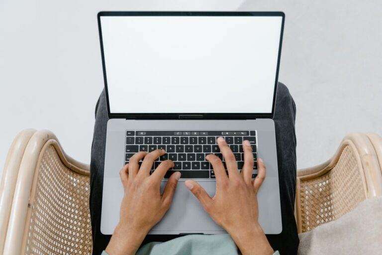Maladie de Charcot : un implant cérébral utilisé à domicile pendant près de 23 mois A person typing on a laptop with a blank screen, viewed from above in a casual setting.