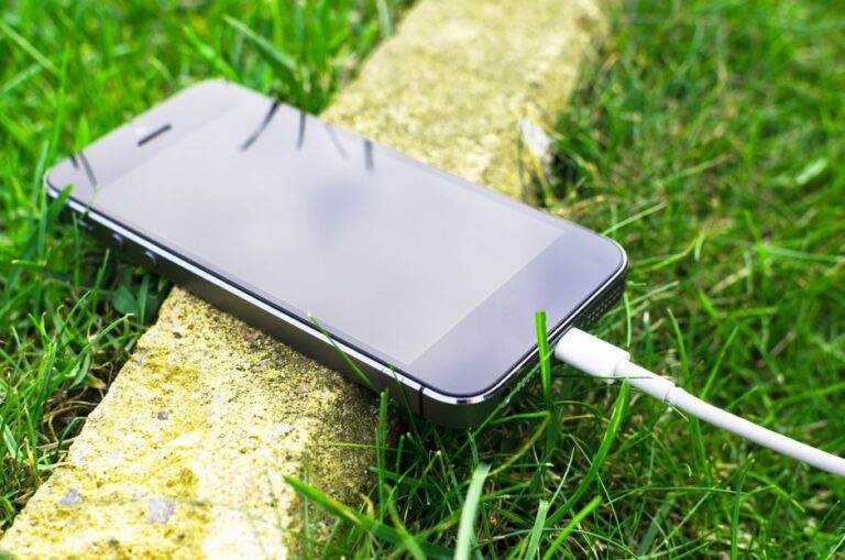 Galaxy S26 en feu en Inde : le modèle reste à confirmer A smartphone with a charging cable rests on grass outdoors, showcasing modern technology in nature.