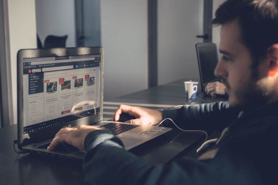 Firefox : contourner les réponses IA de Google avec udm=14 Adult man using laptop to browse an online marketplace in a modern office.