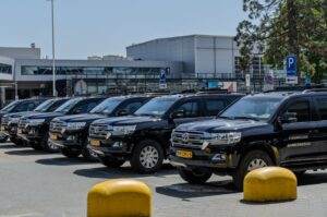Black SUV police vehicles lined up at an airport parking area under clear skies.