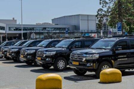 Black SUV police vehicles lined up at an airport parking area under clear skies.