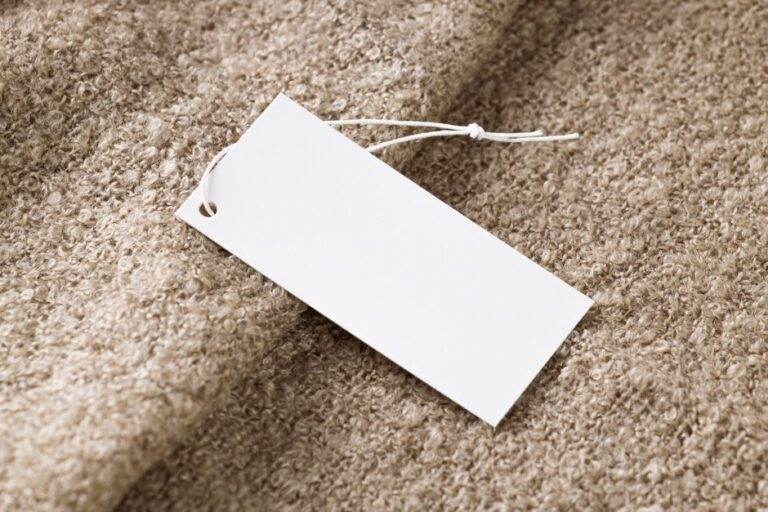 Hausse du prix de l’iPhone 17 : ce que dit la rumeur du 10 août 2026 Close-up of a blank white price tag on textured beige fabric, ideal for branding use.