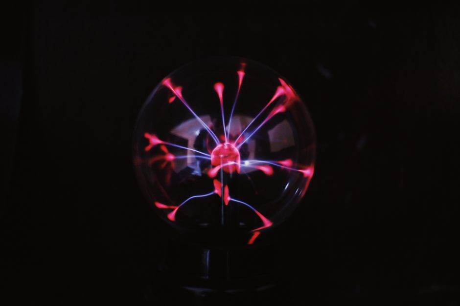 Crystal glass plasma ball with glowing electric lights inside placed in dark room
