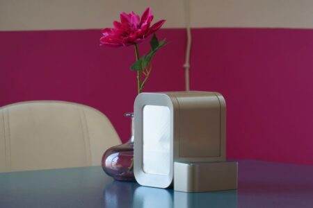 IKEA UPPÅTVIND à 29,99 euros : filtre, débit et limites Elegant interior setting featuring a sleek air purifier and vibrant pink flower in a vase on a table.