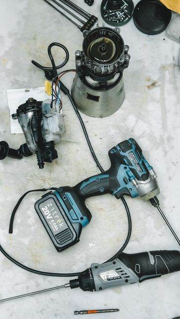 Flat lay of DIY repair tools and disassembled appliance parts on a workbench.
