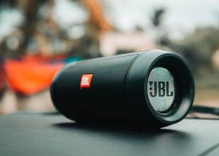 JBL Pulse 6 : IP68, USB-C et commandes physiques, mais une autonomie inchangée Focused shot of a black JBL portable speaker on a surface, ideal for technology concepts.