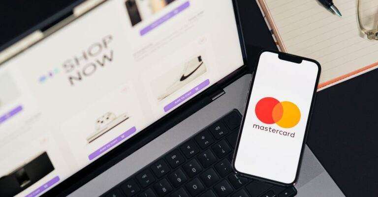 Laptop and smartphone with Mastercard logo, illustrating online shopping and digital payments.