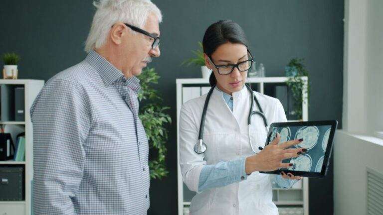 IA en santé en 2026 : le contrôle a un prix Medical professional reviewing brain scans with an elderly man in a clinic.