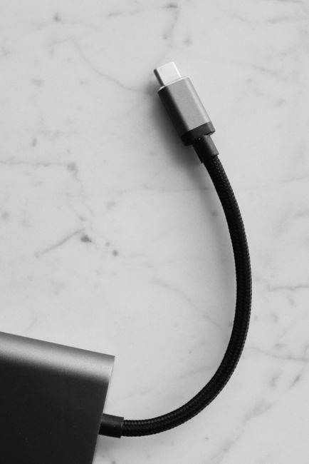 Minimalist black and white photograph of a USB-C cable on a marble background.