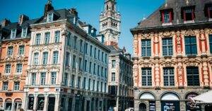 Ornate townhouses and belfry in Lille's Grand Place on a sunny day, showcasing local landmarks.