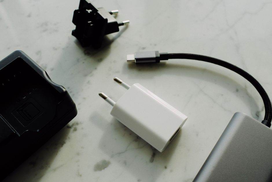 Set of various modern charging unit with adapter and small external battery pack with short cable placed on white marble table