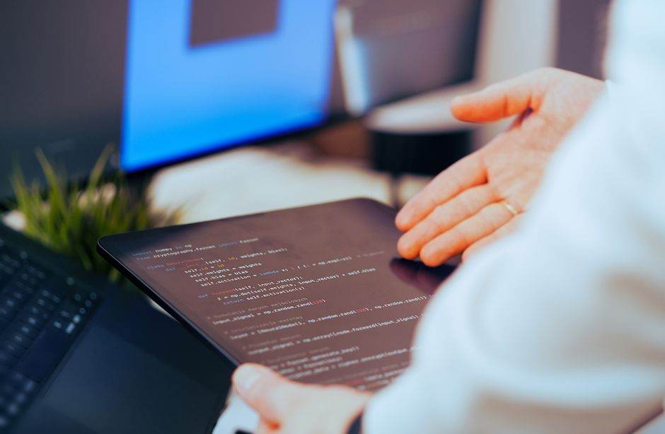 Meta voulait automatiser le travail. Les chiffres ont freiné le plan Software developer analyzing code on a tablet in a modern office workspace.