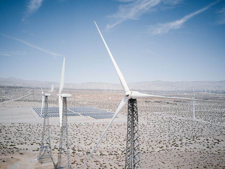 Wind turbines and solar panels generating renewable energy in a desert landscape.