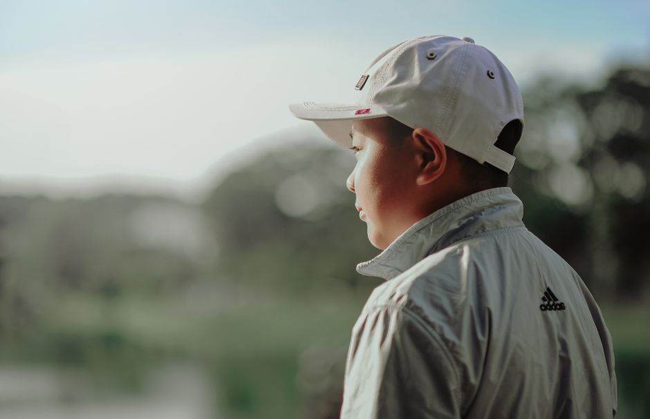 Implants à conduction osseuse en 2026 : indications, coûts et limites A boy wearing a white cap and jacket looks thoughtfully into the distance outdoors.