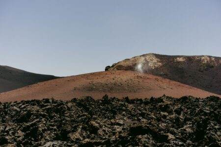 Mars en 2026 : eau, chaleur et biosignatures sous la surface A breathtaking view of a barren volcanic landscape with rugged rocky terrain under clear skies.
