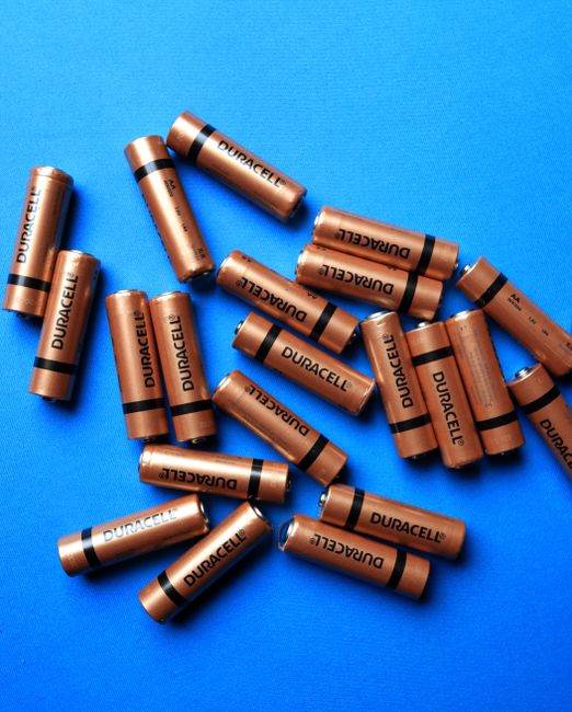A collection of Duracell batteries scattered on a vibrant blue surface, showcasing energy storage.