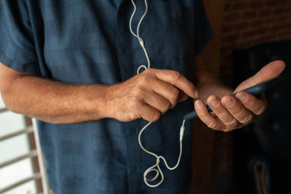 A person interacting with a smartphone while listening to music indoors, captured intimately.