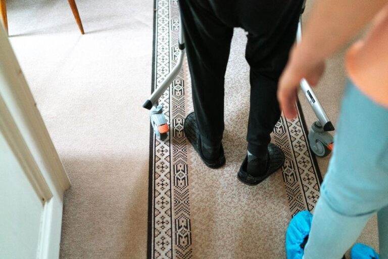 Franchir un obstacle ne se résume pas à sa hauteur A senior person with a walker assisted by a caregiver in a cozy indoor setting.