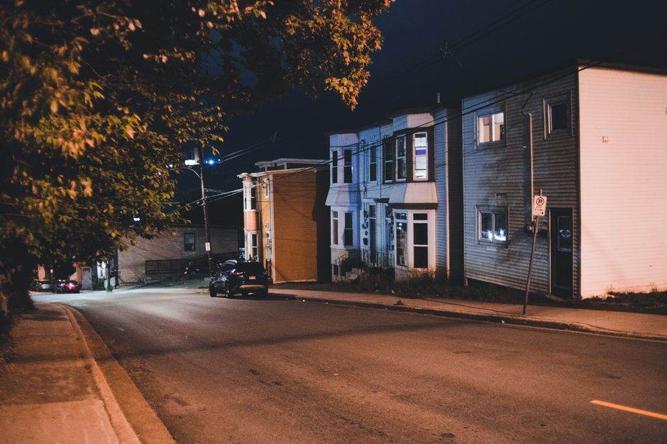 A serene empty urban street at night with residential houses and streetlights.